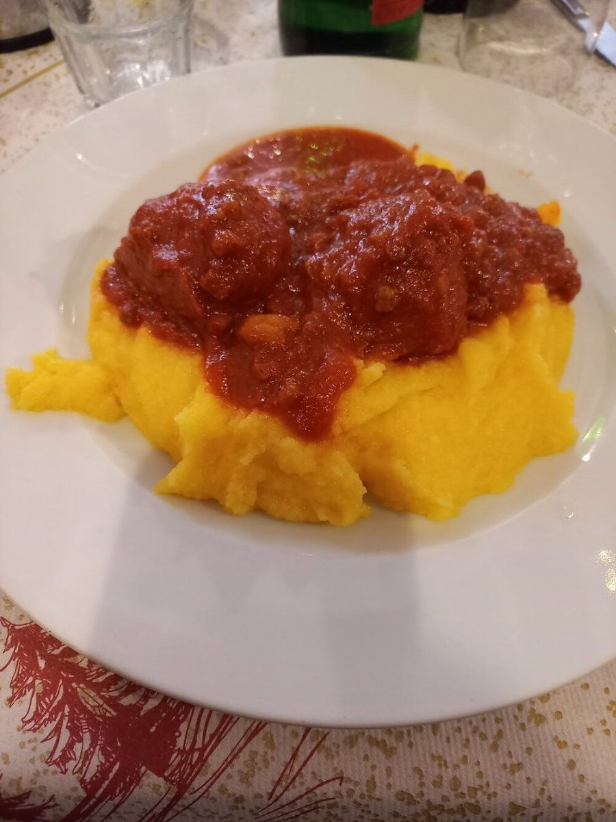 Polenta gialla con polpette al sugo di pomodoro in un piatto bianco.